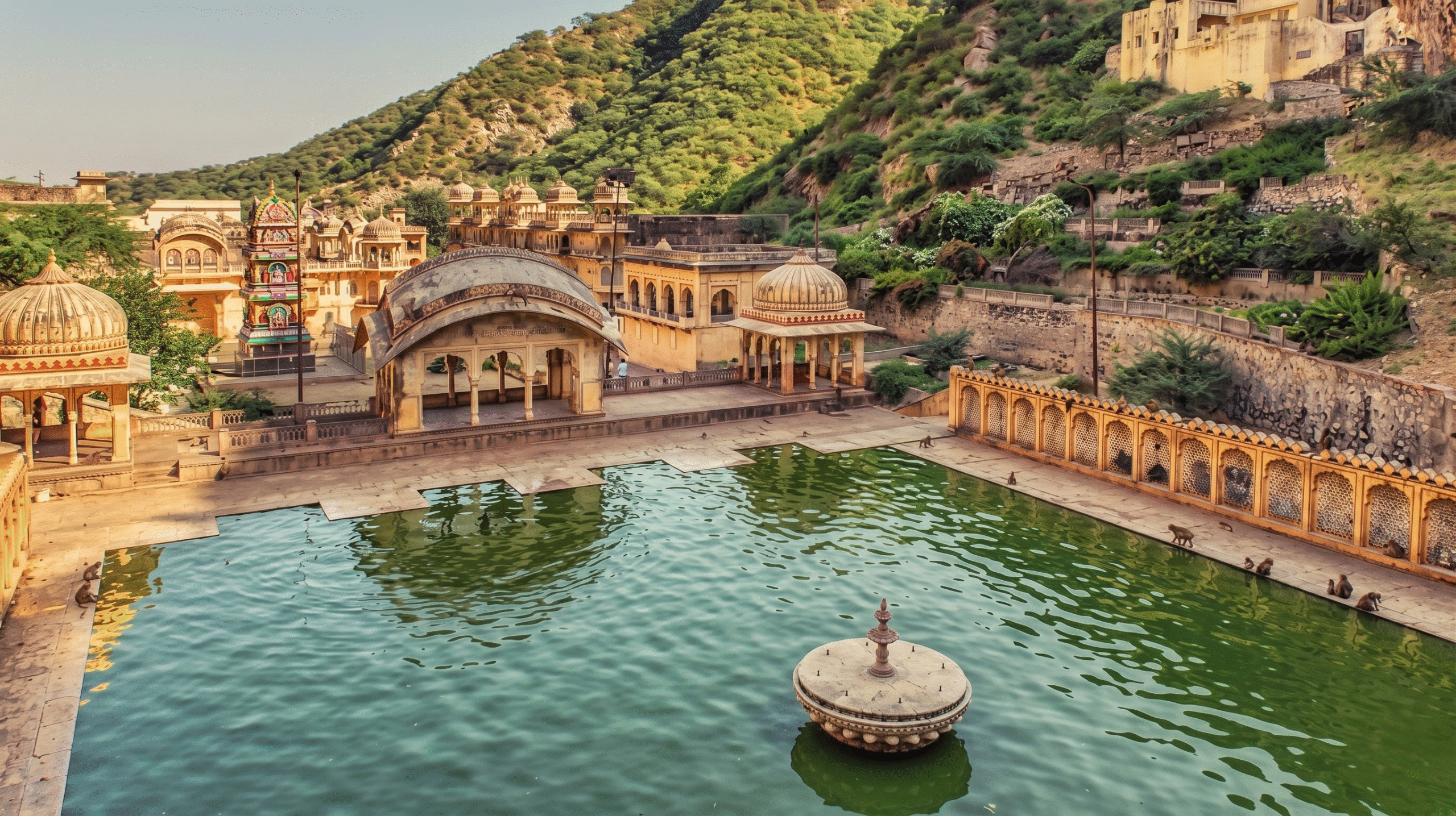 The pink sandstone pavilions and sacred stone water tanks of Galta Ji Monkey Temple nestled in the Aravalli hills of Jaipur